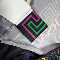 Interior detail of Versace Fall Winter 2021 La Greca pleated skirt showing pink and green Greek Key woven label, fabric lining and multicolor geometric print.