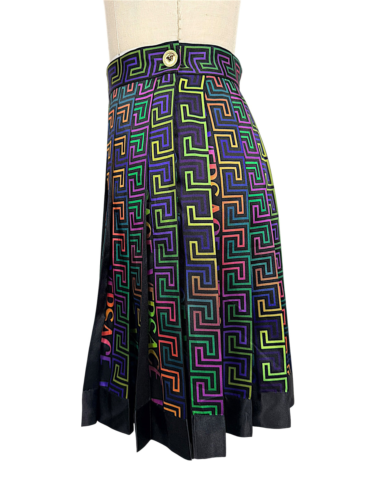 Side view of Versace FW 2021 La Greca skirt featuring a gold-tone Medusa button at the high waistband and multicolor pleated geometric fabric.