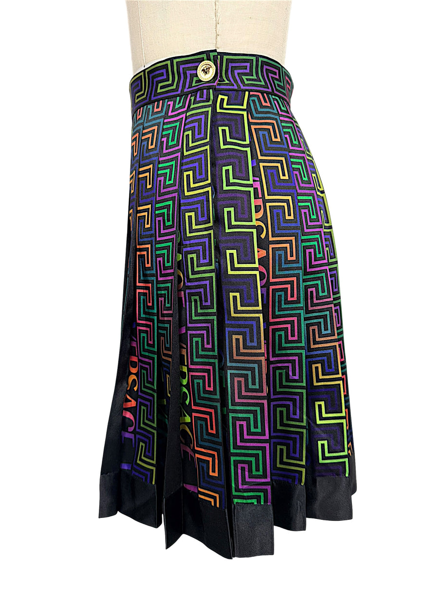 Side view of Versace FW 2021 La Greca skirt featuring a gold-tone Medusa button at the high waistband and multicolor pleated geometric fabric.