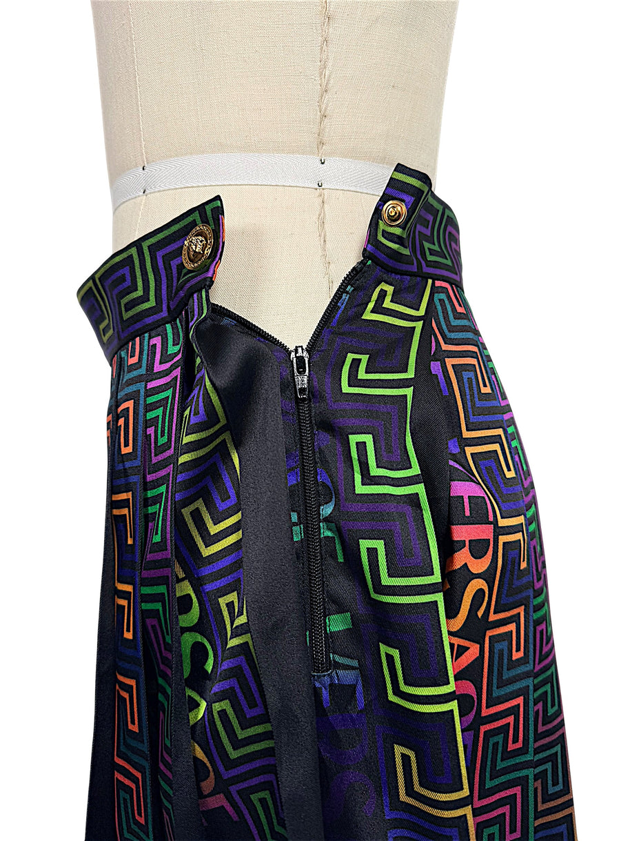 Close-up of Versace La Greca pleated skirt side zipper, Medusa button fastening and multicolor geometric print waistband.