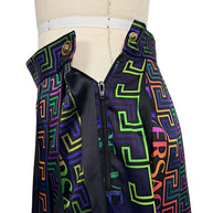 Close-up of Versace La Greca pleated skirt side zipper, Medusa button fastening and multicolor geometric print waistband.
