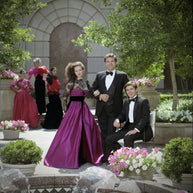 Archival photograph of American fashion designer Victor Costa with models wearing his signature eveningwear during the late 1980s, illustrating the glamorous era and design aesthetic associated with his formal collections. This image is provided for historical context and does not depict the featured gown.