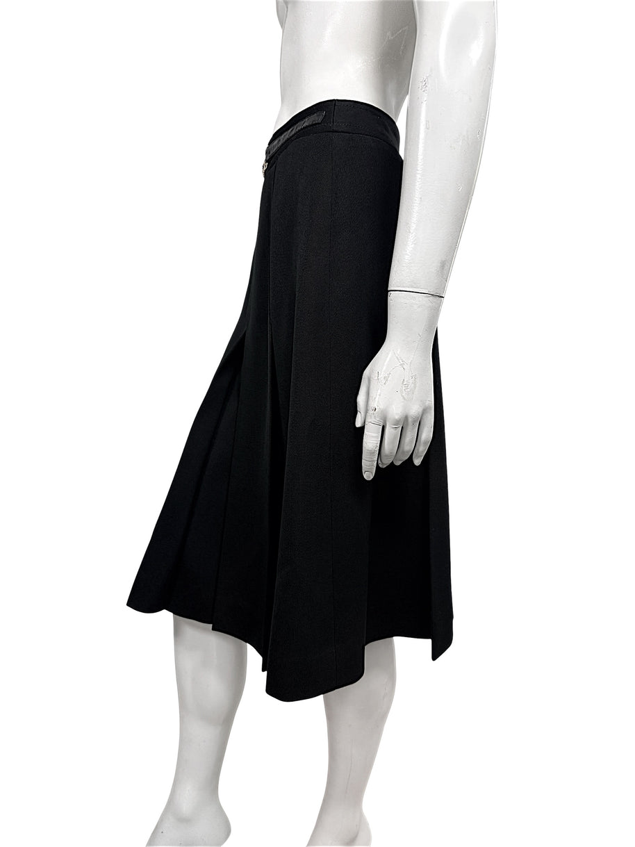 Opposite side view of vintage Céline black wool skirt showing the flared midi silhouette, deep pleats, and integrated leather waistband.