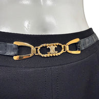 Detailed close-up of gold-tone Céline Double-C logo hardware with rope-style oval frame and black leather belt on vintage wool skirt.