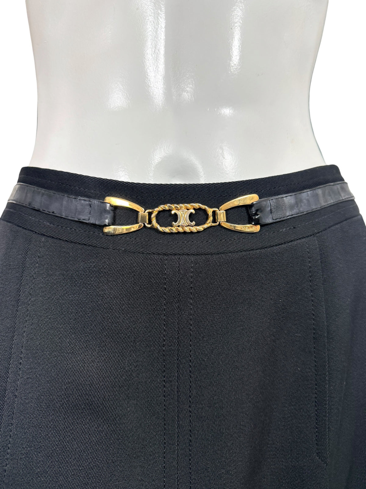 Close-up of vintage Céline skirt featuring a black leather belt, gold-tone interlocking Double-C emblem, and tailored black wool waistband.