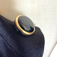 Macro detail of authentic vintage Chanel black enamel and gold-tone logo button.