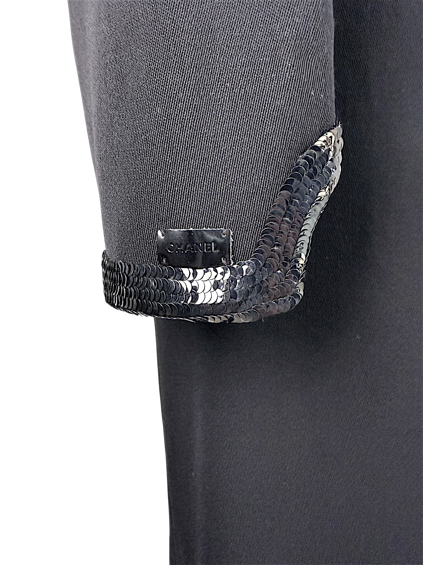 Close detail of Chanel logo plaque and tonal sequined trim on sleeve cuff
