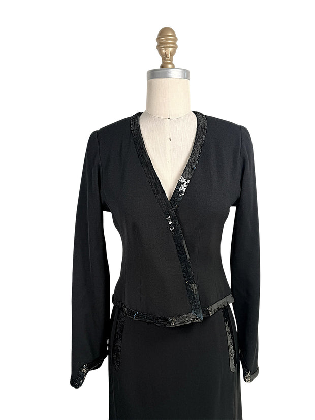 Close front view of vintage Chanel black skirt suit with black sequin trim and tailored wrap jacket silhouette