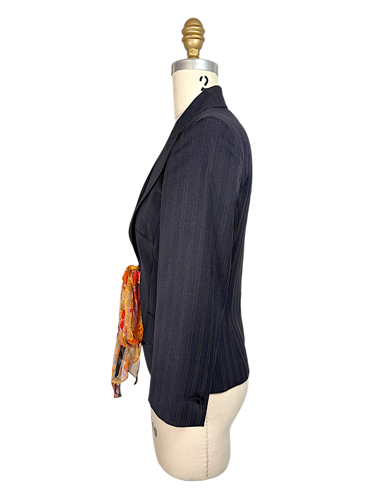 Opposite side view of vintage D&G Dolce & Gabbana navy pinstripe fitted blazer highlighting structured shoulder, tailored sleeve and colorful silk waist tie.