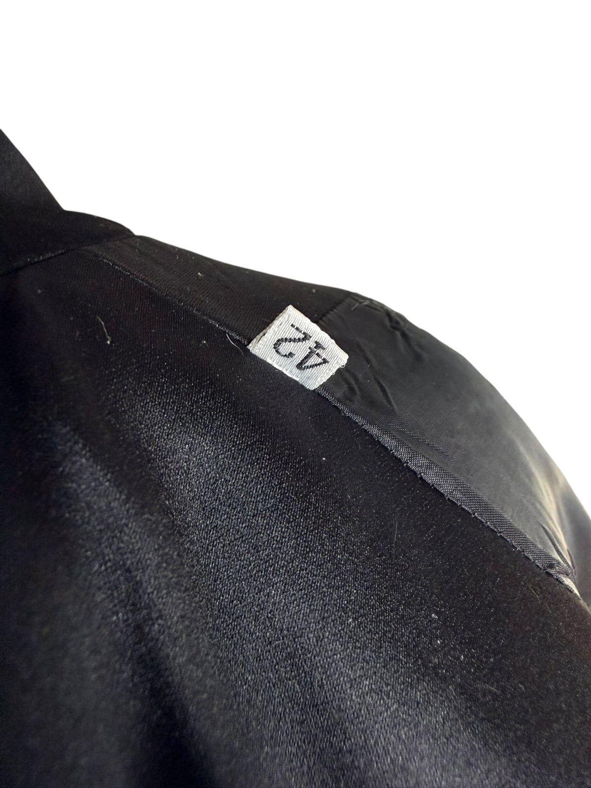 Close-up of the Italian size 42 tag inside a vintage Gianni Versace Couture black blazer, showing the label against black fabric and lining.