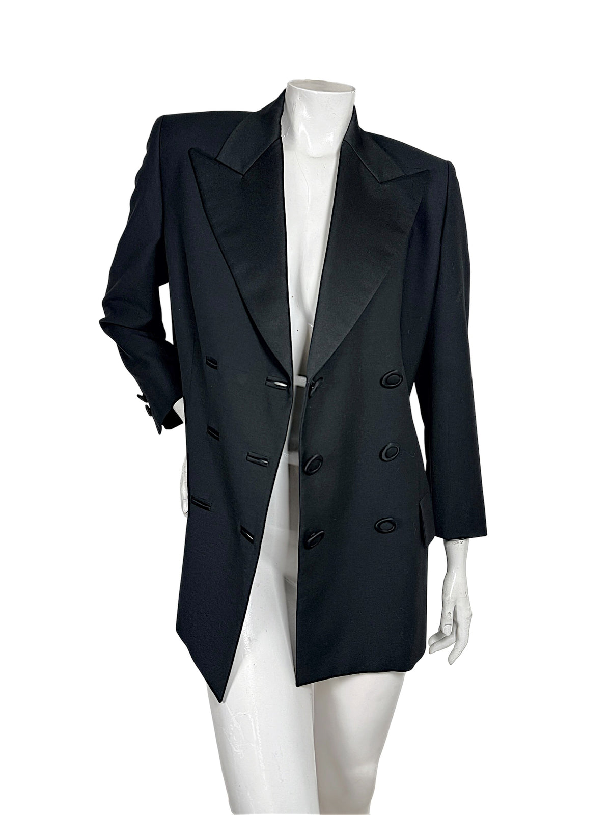 Vintage Gianni Versace Couture black double-breasted blazer worn open on a mannequin, displaying oversized peaked lapels, fabric-covered buttons and longline cut.