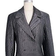Close-up of vintage Guy Laroche Paris black quilted jacket showing double-breasted covered buttons, lapels, and geometric stitching.
