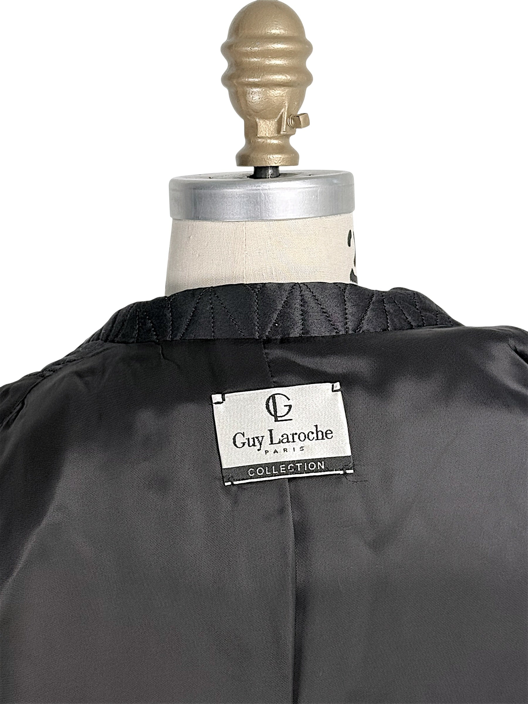 Close-up of vintage Guy Laroche Paris Collection designer label inside black quilted jacket.